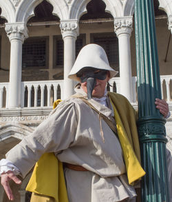 Portrait of man wearing hat standing against building