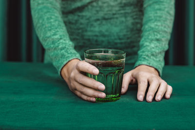 Close-up of hand holding glass of drink on table