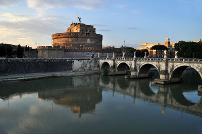 Arch bridge over river against buildings in city