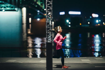 Woman with pink umbrella standing at night