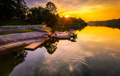 Boats moored at pier in lake during sunset