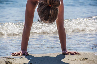 Close-up of woman doing handstand on shore at beach