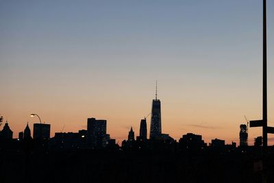 One world trade center in city against sky during sunset