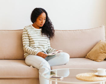 Young woman sitting on sofa at home