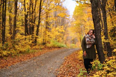 Woman standing by tree in forest during autumn