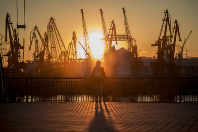 Woman working at harbor against sky during sunset