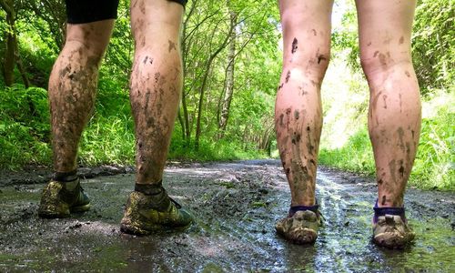 Low section view of couple with dirty legs in forest