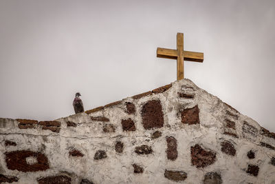 Low angle view of cross on building against sky