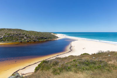 Scenic view of beach against clear blue sky