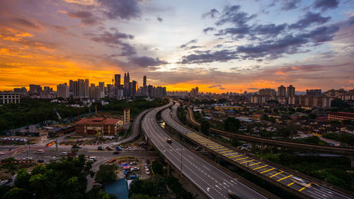 High angle view of street amidst buildings against sky during sunset
