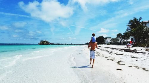 Full length of man and son on beach against sky