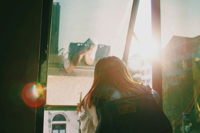 Young woman against sky seen through window