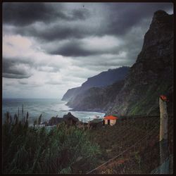 Scenic view of sea and mountains against storm clouds