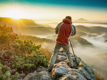 Photographer talking photos using slr camera in fall autumn forest. man photographing mountains.