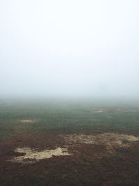 Scenic view of field in foggy weather against sky