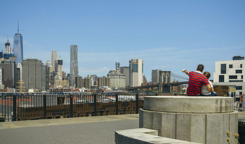 Rear view of woman standing by cityscape against clear sky