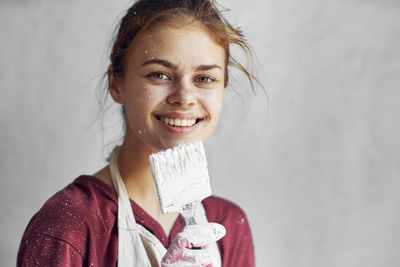 Portrait of young woman standing against wall