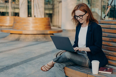 Young woman using laptop while sitting on table
