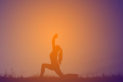 Silhouette woman doing anjaneyasana on field during sunset