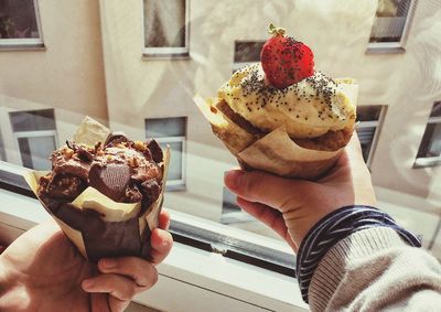 Cropped hands having dessert by window