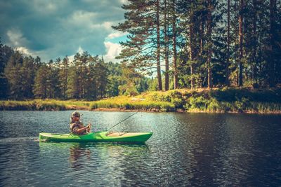 Man kayaking on lake against trees