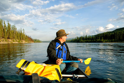 Man in canoe on yukon river against sky