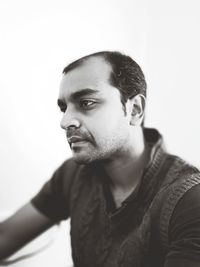 Portrait of young man looking away against white background