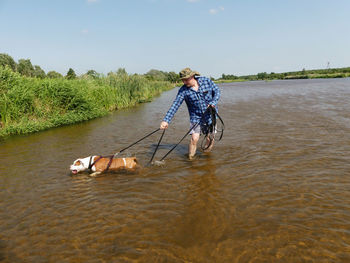 Man with dog in water against sky