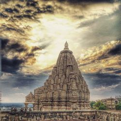 Silhouette of temple against cloudy sky