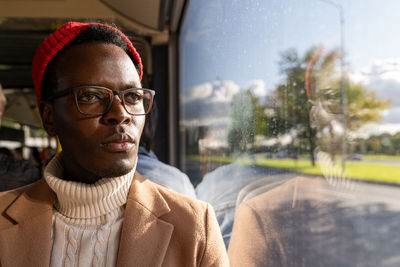African american traveler man wearing glasses, looking at window, traveling by public transportation