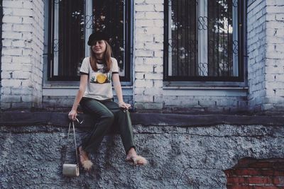 Portrait of teenage girl sitting on window sill