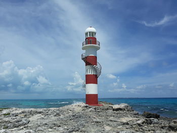 Lighthouse by sea against sky