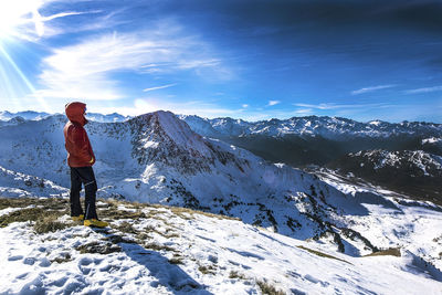 Rear view of person standing on snowcapped mountain against sky