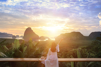 Rear view of woman standing at sunset