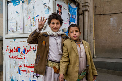 Portrait of boy standing against graffiti wall