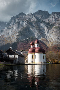 Built structure by lake and mountains against sky