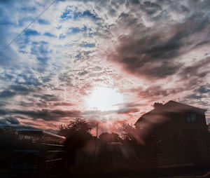 Low angle view of sun shining through clouds