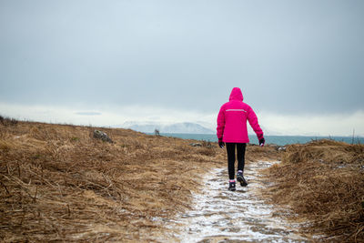 Rear view of woman walking on snow covered land