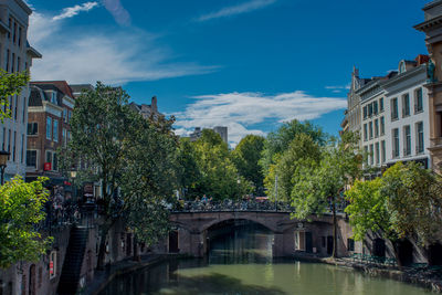 Arch bridge over river amidst buildings against sky