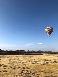 Hot air balloon flying over field against sky