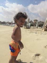 Boy standing on beach against sky