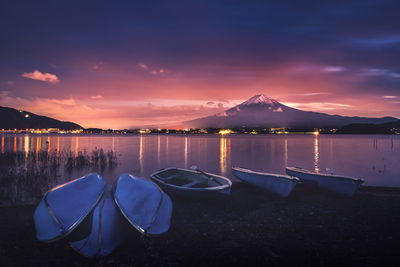 Boats moored on lake against sky during sunset