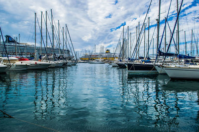 Sailboats moored at harbor against sky