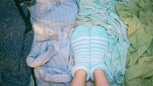 Low section of person wearing blue socks on bed