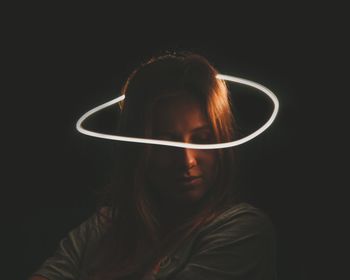 Close-up portrait of a young woman over black background