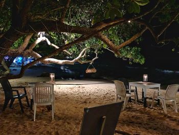 Empty chairs and tables at beach during night
