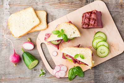 Fresh sandwiches with pastrami, cucumber and radish on a cutting board. american snack