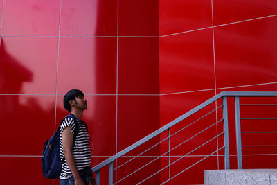 Full length of woman standing against red wall