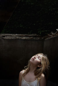 Portrait of young woman standing against wall