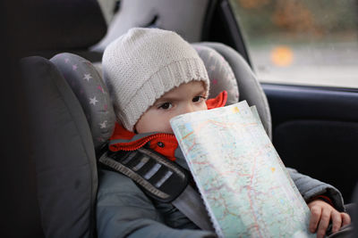 Adorable little boy exploring a map during his road trip on vacations with his parents. happy family
